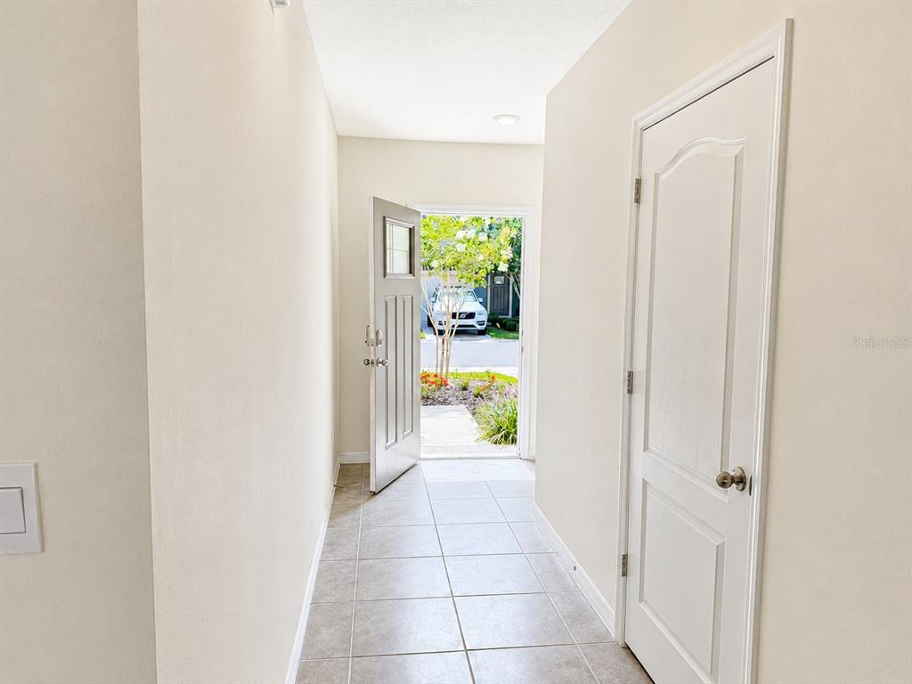 A tiled entryway features a white door opening to a view of a parked car — 13 BELLA OAKS DR DRIVE, PORT ORANGE, FL