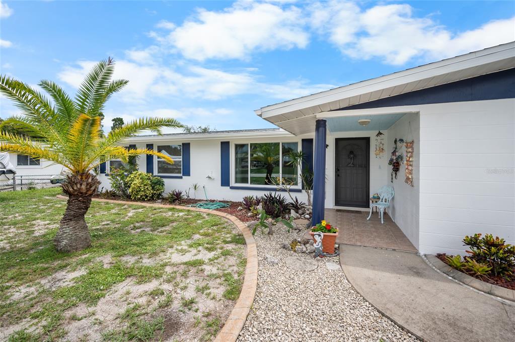 A white single-story house features a palm tree, a gravel garden, and a covered entryway — 2113 GEORGIA AVENUE, ENGLEWOOD, FL