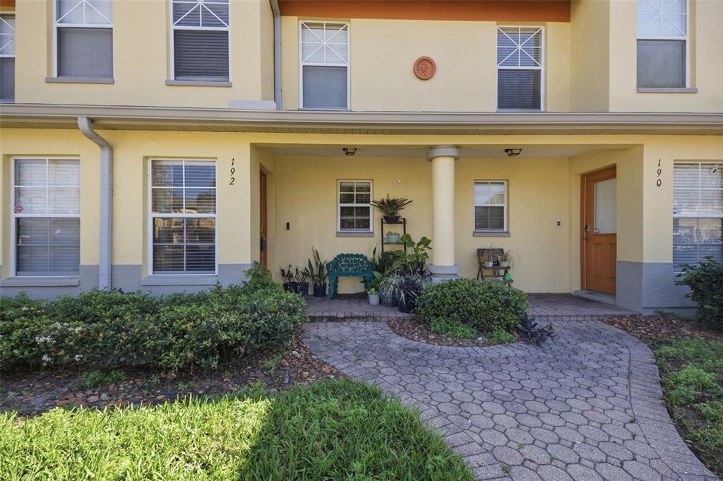 A paved walkway leads to the covered entryway of a two-story yellow stucco building — 192 COQUINA BAY DRIVE, ST PETERSBURG, FL