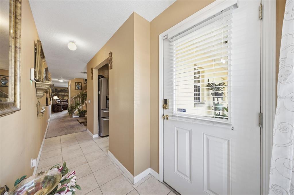 A tiled entryway leads to a carpeted hallway with a view of a staircase — 192 COQUINA BAY DRIVE, ST PETERSBURG, FL