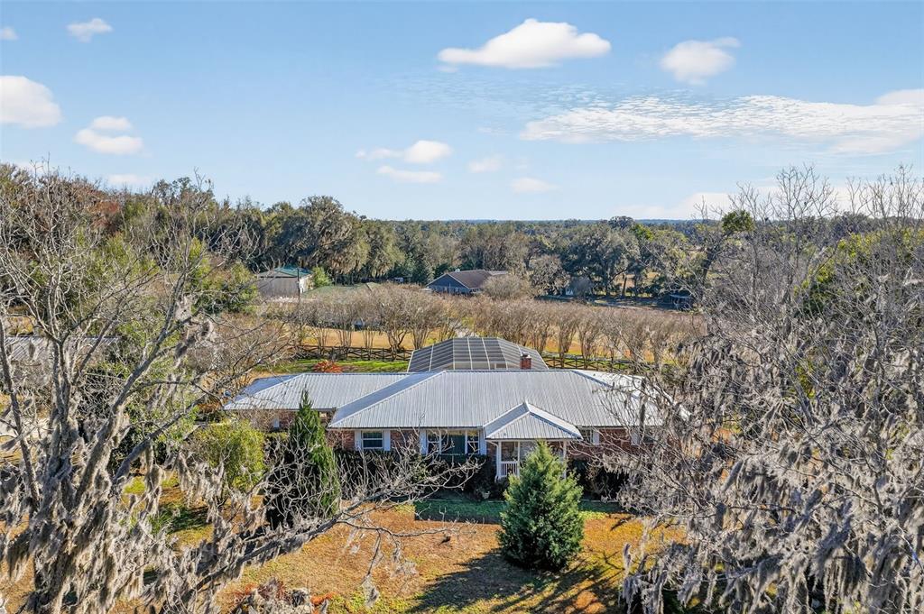 An aerial view shows a single-story house with a metal roof and a screened pool — 2230 SW 87TH PLACE, OCALA, FL
