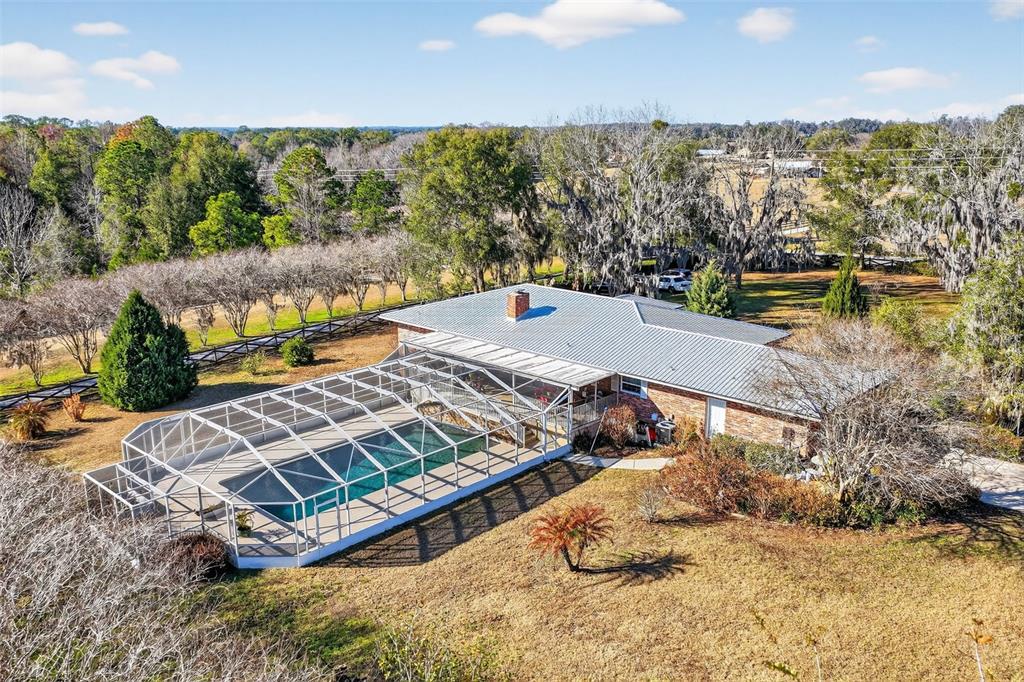 An aerial view shows a brick house with a metal roof and a screened pool — 2230 SW 87TH PLACE, OCALA, FL
