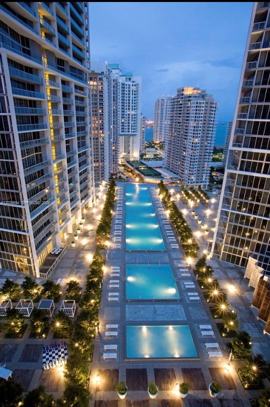 An aerial view of a multi-level swimming pool area between two tall modern apartment buildings — 495 Brickell Ave # 5706, Miami FL 33131, MIAMI, FL