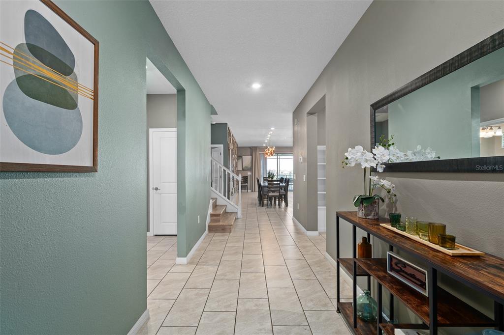 A tiled hallway leads from a foyer toward a dining area with a staircase nearby — 3723 LANA AVENUE, DAVENPORT, FL