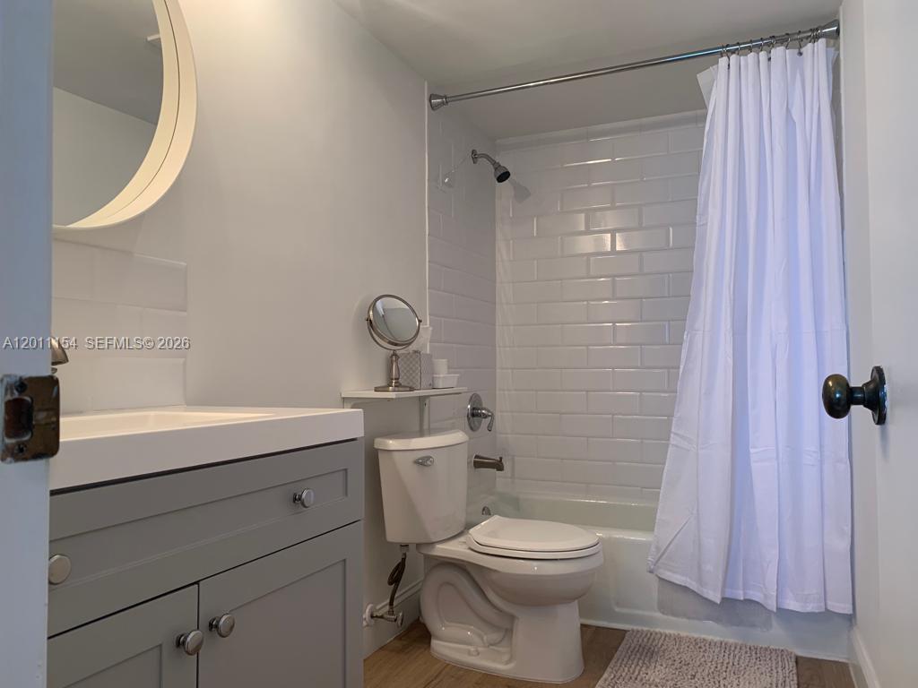 A bathroom features a gray vanity, white subway tile shower surround, and a white toilet — 780 NE 69th St # 506, Miami FL 33138, MIAMI, FL