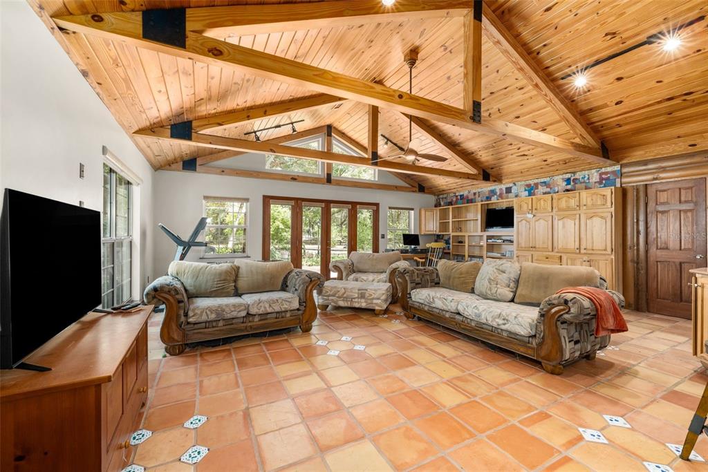 A living room with a vaulted wood ceiling, tile floors, and two patterned sofas — 340 SE 30TH AVENUE, TRENTON, FL