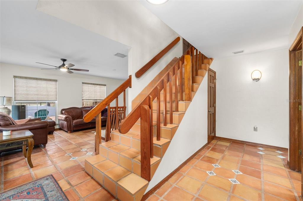 An interior view shows a tiled foyer with a wooden staircase and an adjacent living area — 340 SE 30TH AVENUE, TRENTON, FL