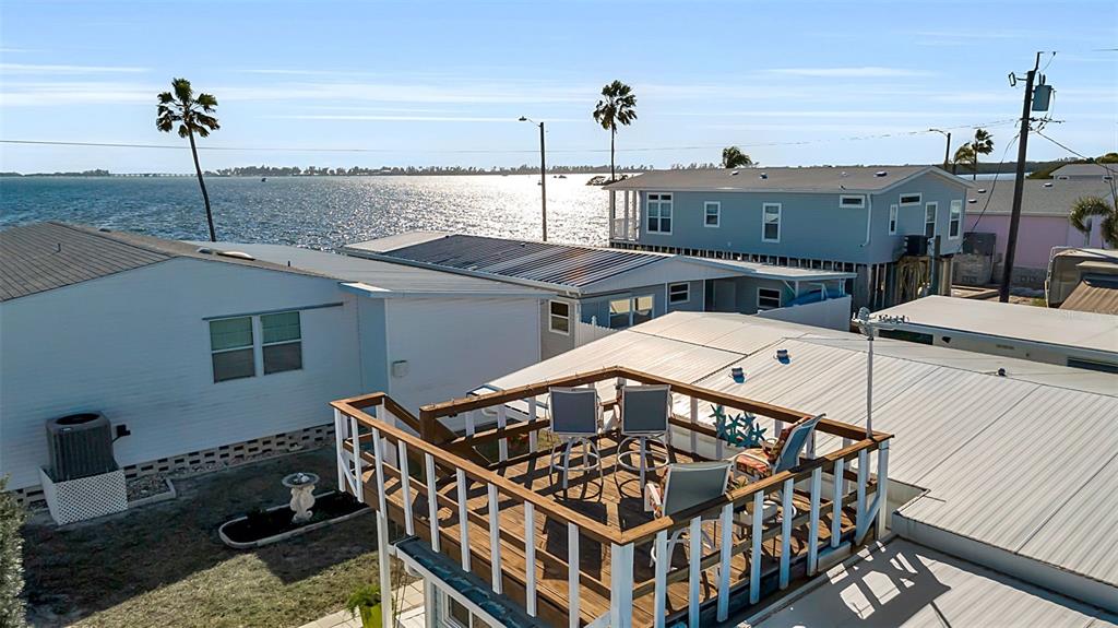 An elevated wooden deck with patio furniture overlooks a body of water and neighboring homes — 10315 CORTEZ ROAD W UNIT 27F, BRADENTON, FL