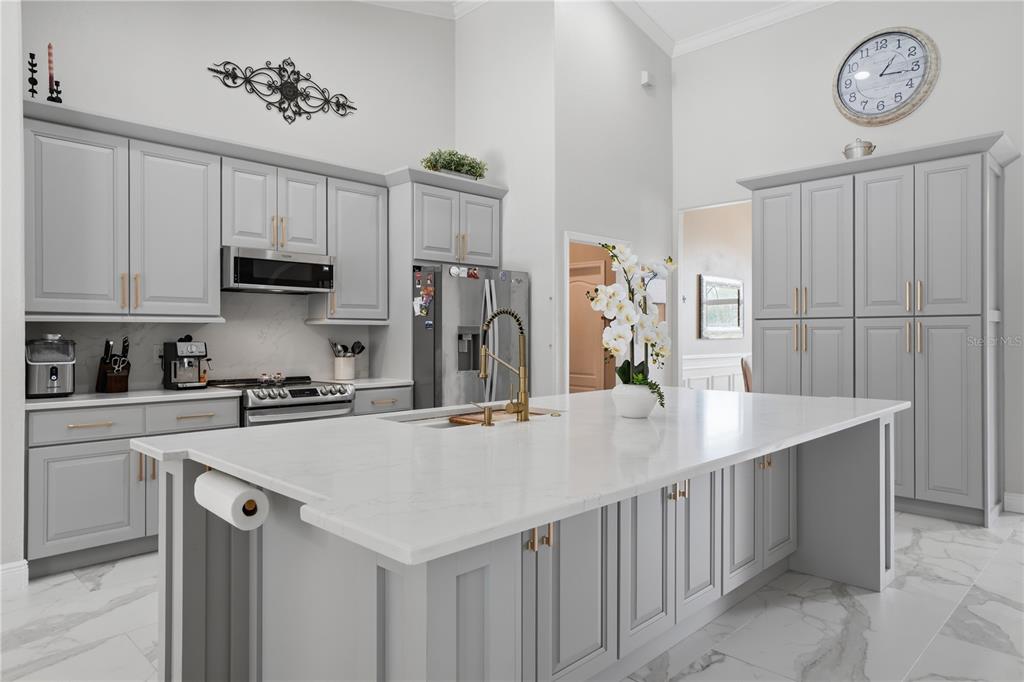 A modern kitchen features gray cabinetry, a large white quartz island, and marble-patterned tile flooring — 510 SONATA COURT, WINTER SPRINGS, FL