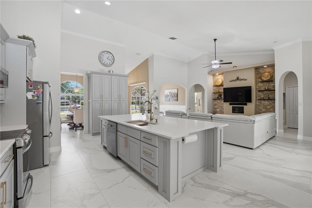 A bright, open-concept kitchen and living area featuring white marble-look tile floors and gray cabinetry — 510 SONATA COURT, WINTER SPRINGS, FL