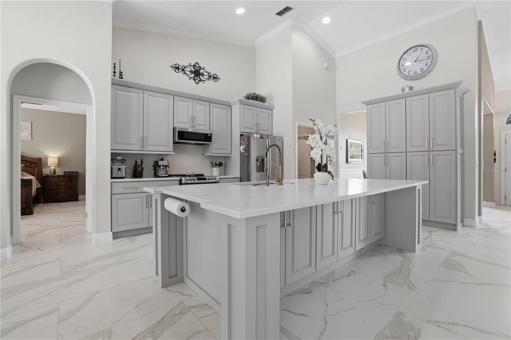 A modern kitchen features light gray cabinetry, a large white quartz island, and marble-look flooring — 510 SONATA COURT, WINTER SPRINGS, FL