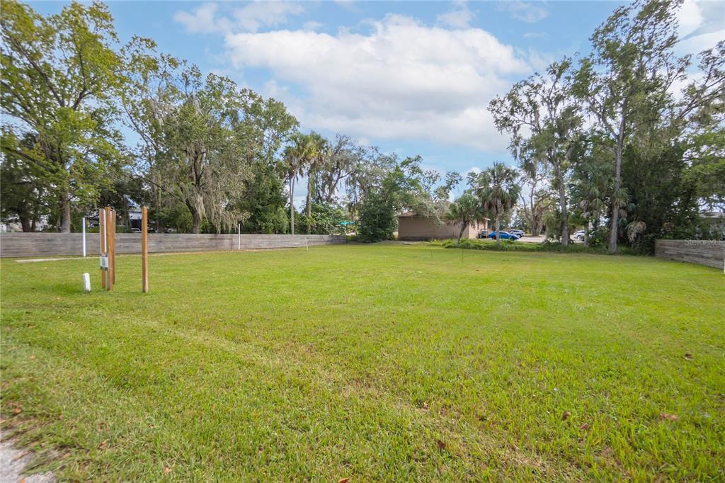 A flat, grassy vacant lot is enclosed by a wooden fence and surrounded by trees — 464 NE 2ND STREET, CRYSTAL RIVER, FL