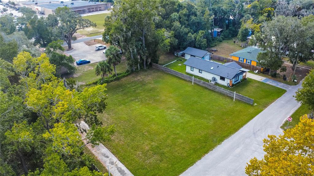 An aerial view shows a vacant grassy lot next to a house with a fence — 464 NE 2ND STREET, CRYSTAL RIVER, FL