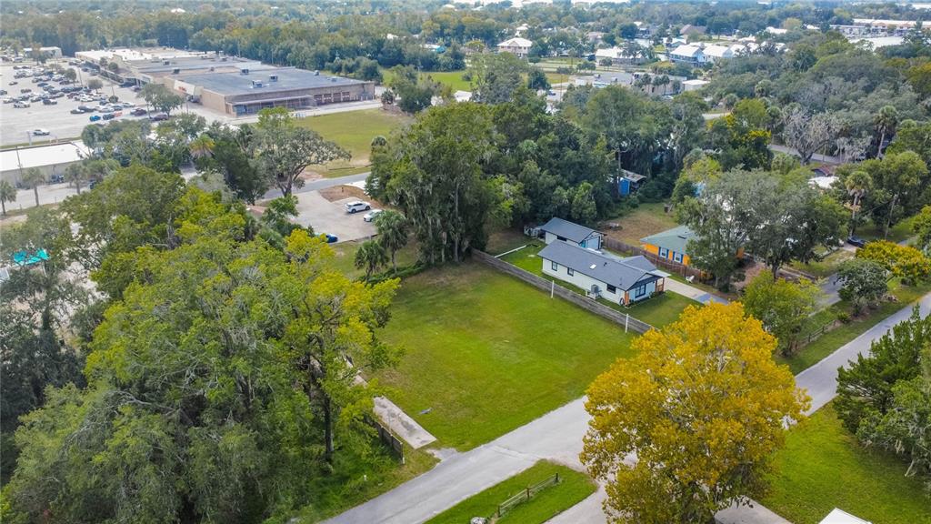 An aerial view shows a vacant grassy lot situated next to a small residential house — 464 NE 2ND STREET, CRYSTAL RIVER, FL