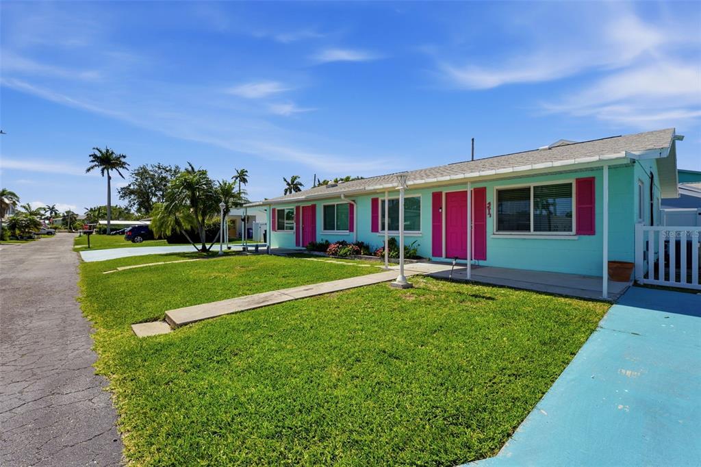 A light blue single-story house with bright pink shutters and doors sits on a lawn — 4517 103RD STREET COURT W, BRADENTON, FL