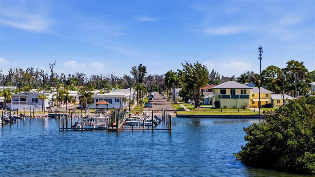 A canal leads to a residential neighborhood with a dock, boats, and several houses — 4517 103RD STREET COURT W, BRADENTON, FL