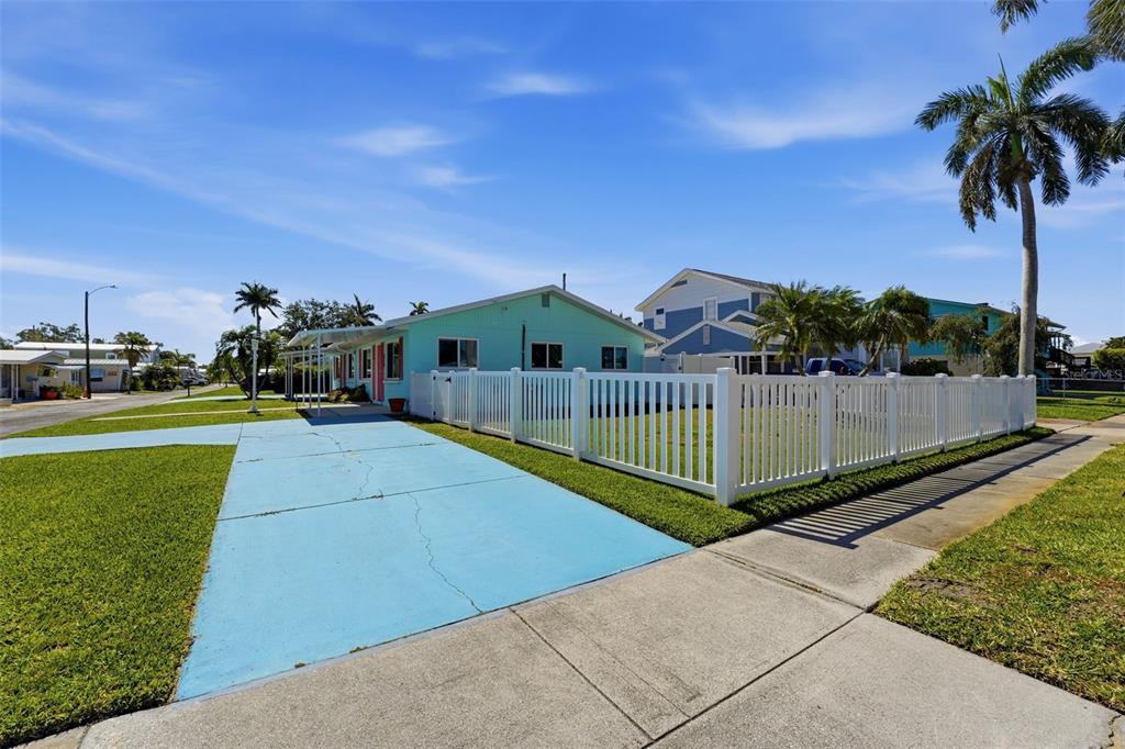 A light blue house with a white picket fence and a painted blue driveway — 4517 103RD STREET COURT W, BRADENTON, FL