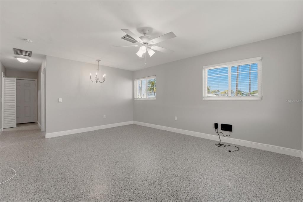 A spacious room with light gray walls, a ceiling fan, and speckled epoxy flooring — 4517 103RD STREET COURT W, BRADENTON, FL