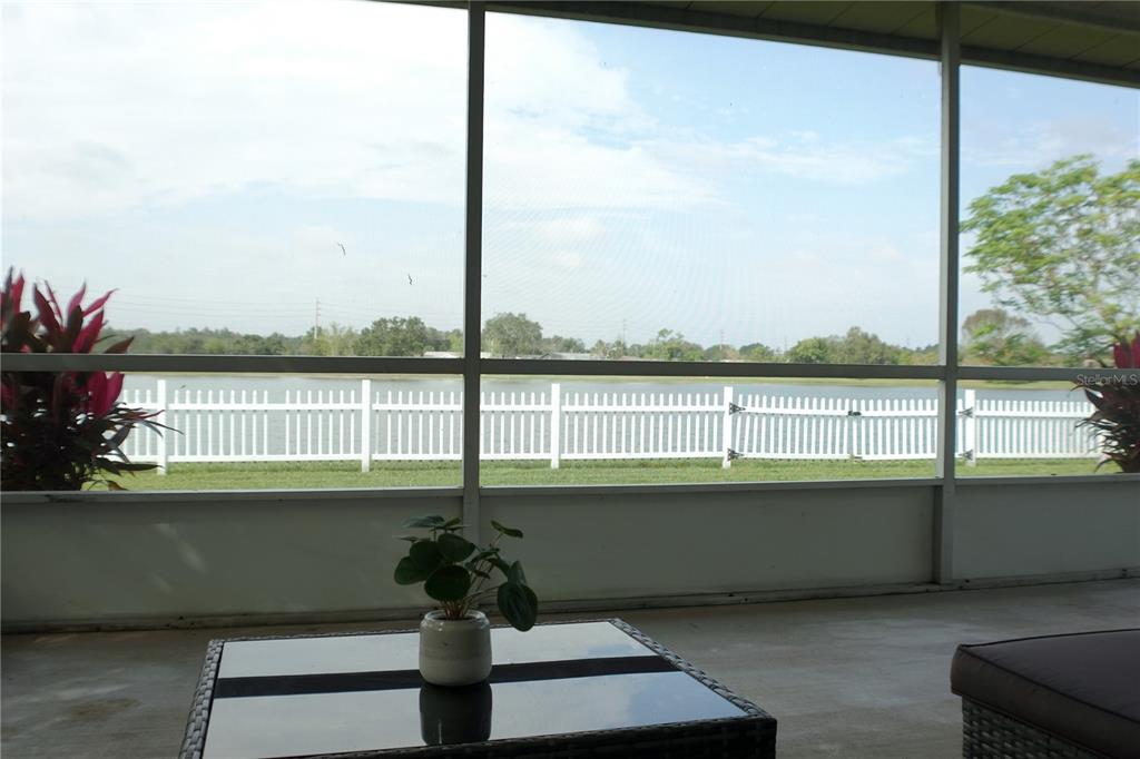 A screened-in porch overlooks a white picket fence and a lake — 957 FLORIDA PARKWAY, KISSIMMEE, FL