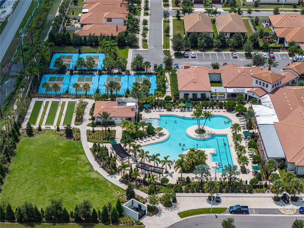 An aerial view shows a community clubhouse with a swimming pool and tennis courts — 17319 HOLLY WELL AVENUE, WIMAUMA, FL