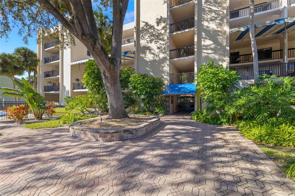 A swimming pool sits in front of a multi-story apartment building with private balconies — 402 TARPON POINT, TARPON SPRINGS, FL