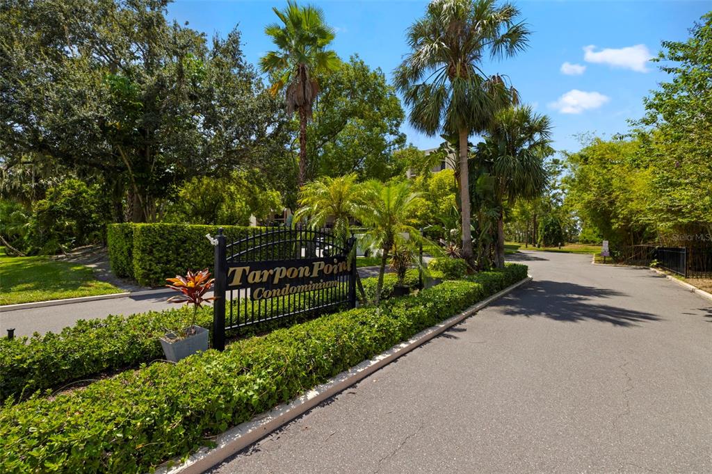 A paved walkway leads to the entrance of a multi-story apartment building with balconies — 402 TARPON POINT, TARPON SPRINGS, FL