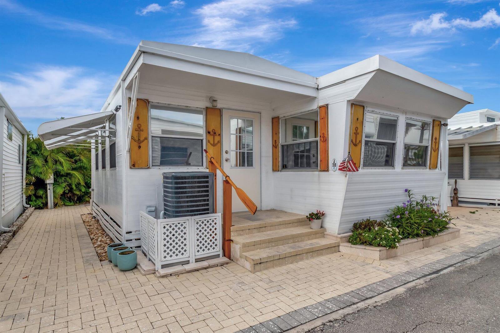 A white mobile home with a paved driveway, an air conditioning unit, and nautical decor — 18 Juniper Drive # J, Briny Breezes FL 33435, BRINY BREEZES, FL