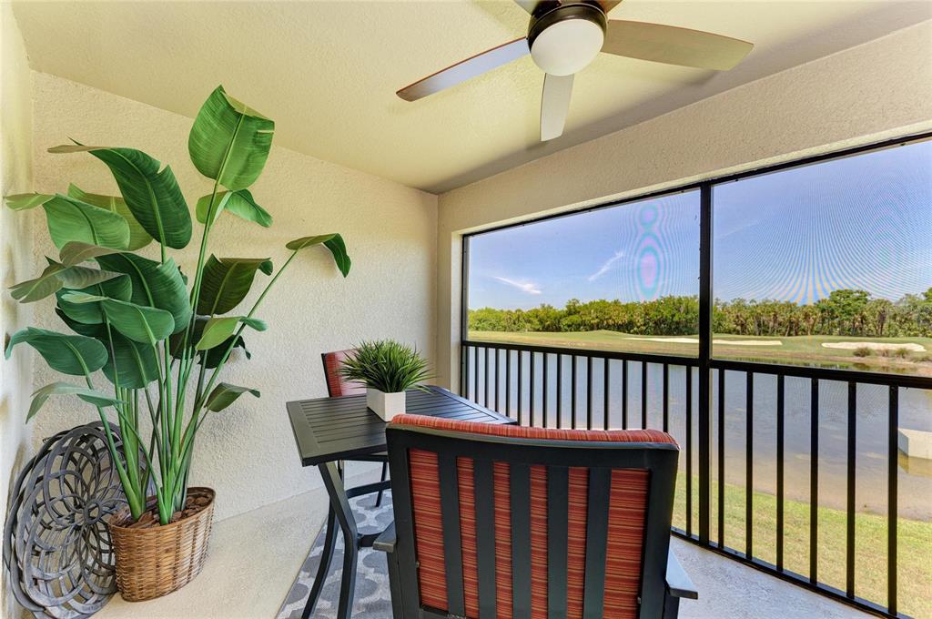 A screened-in balcony features a ceiling fan, a small dining set, and a water view — 6819 GRAND ESTUARY TRAIL UNIT 205, BRADENTON, FL