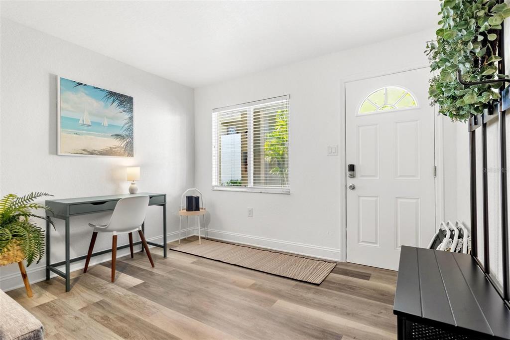A bright entryway features wood-look flooring, a desk, a window with blinds, and a front door — 2704 2ND STREET UNIT 2, INDIAN ROCKS BEACH, FL