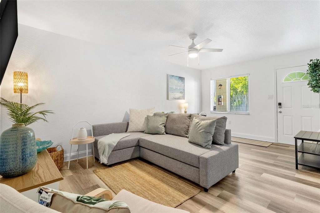 A living room features a grey sectional sofa, light wood-look flooring, and a ceiling fan — 2704 2ND STREET UNIT 2, INDIAN ROCKS BEACH, FL