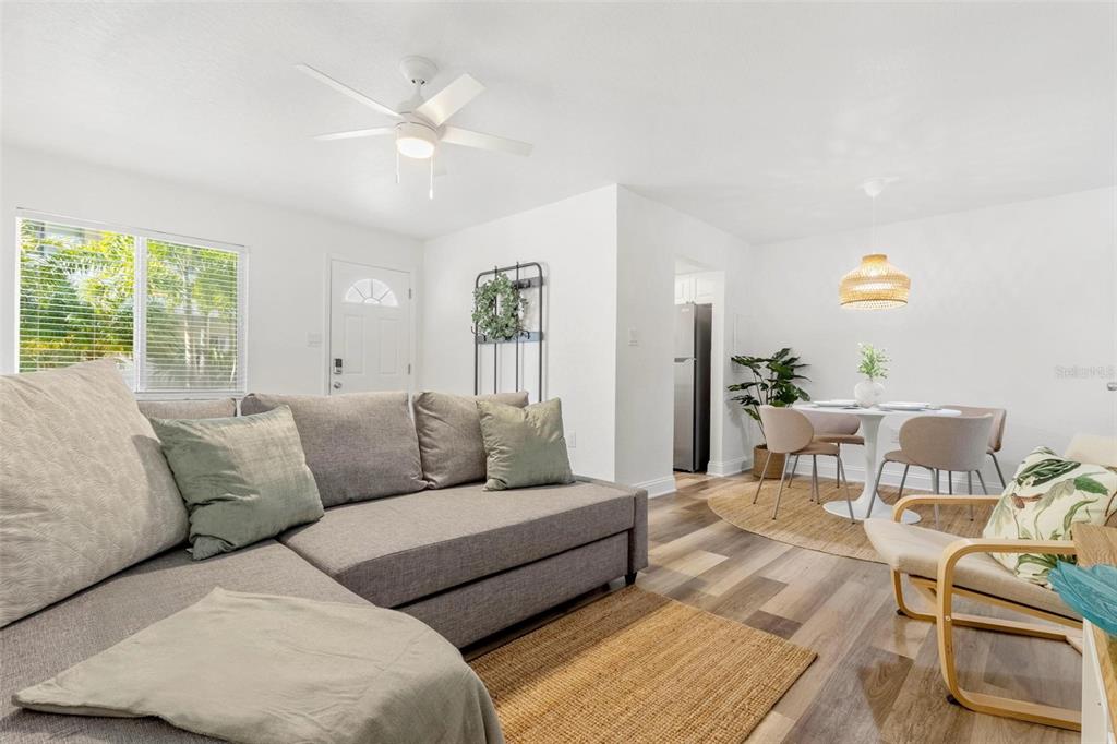 A living room with a gray sectional sofa, wood-look flooring, and an adjacent dining area — 2704 2ND STREET UNIT 2, INDIAN ROCKS BEACH, FL