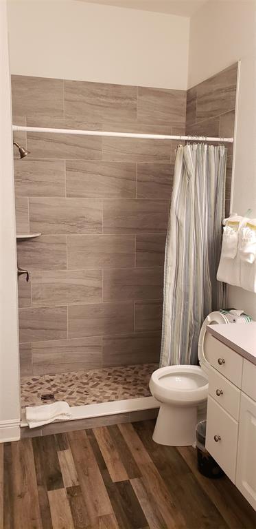 A bathroom features a walk-in tiled shower, a white toilet, and wood-look flooring — 21032 PICASSO COURT UNIT 205, LAND O LAKES, FL
