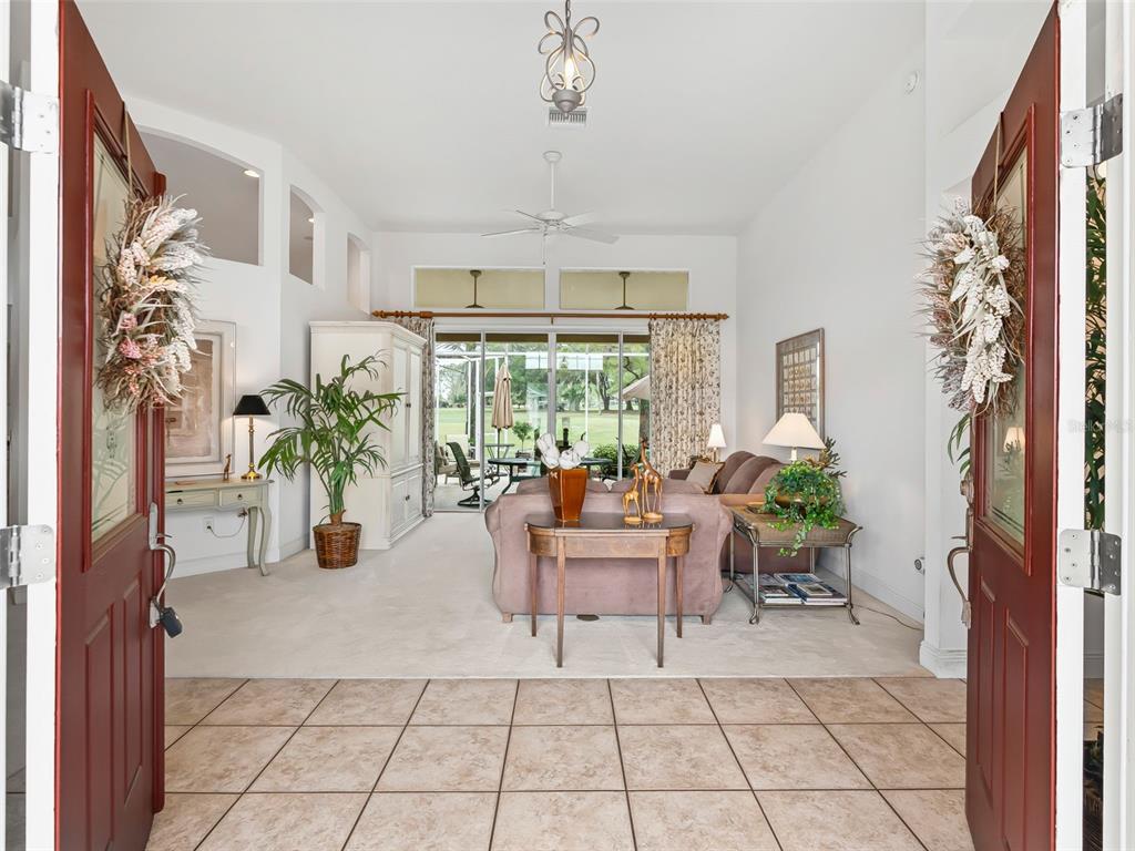 A view from an entryway into a living room with tile floors and sliding glass doors — 8755 SE 177TH GRASSMERE STREET, THE VILLAGES, FL