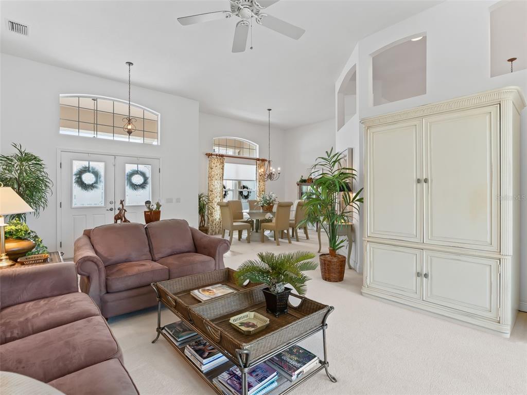 A living room features a brown sofa, a wicker coffee table, and a dining area — 8755 SE 177TH GRASSMERE STREET, THE VILLAGES, FL