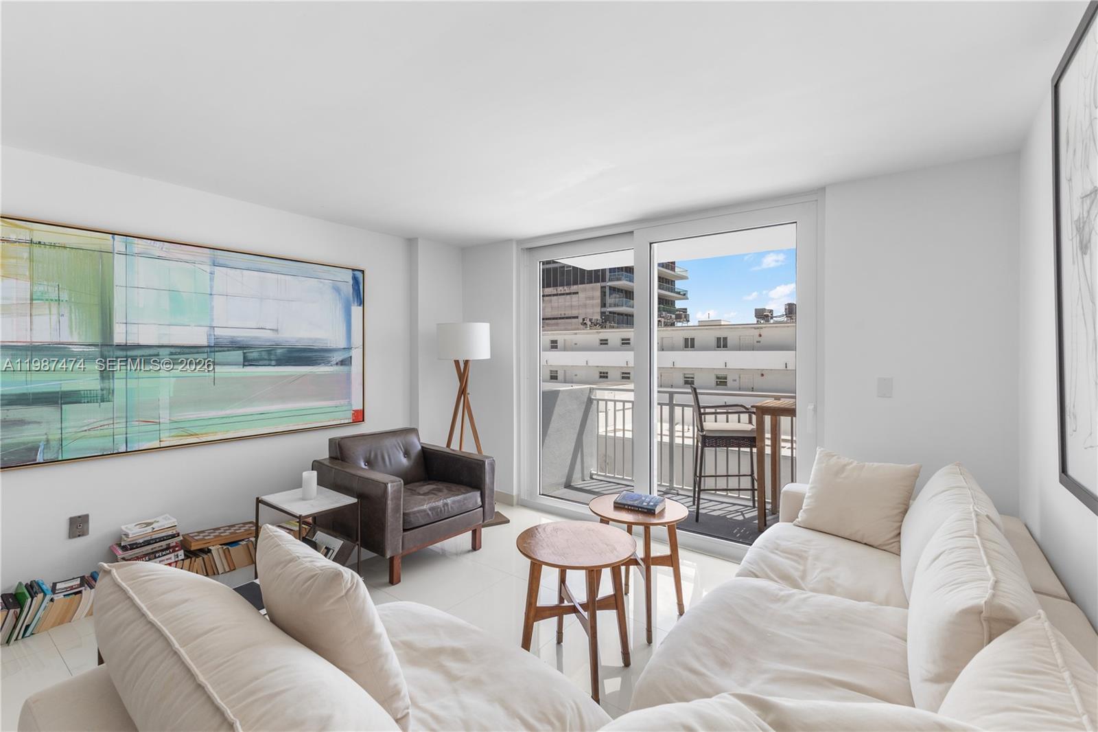 A living room features a white sofa, leather armchair, two small wooden tables, and balcony access — 345 Ocean Dr # 607, Miami Beach FL 33139, MIAMI BEACH, FL
