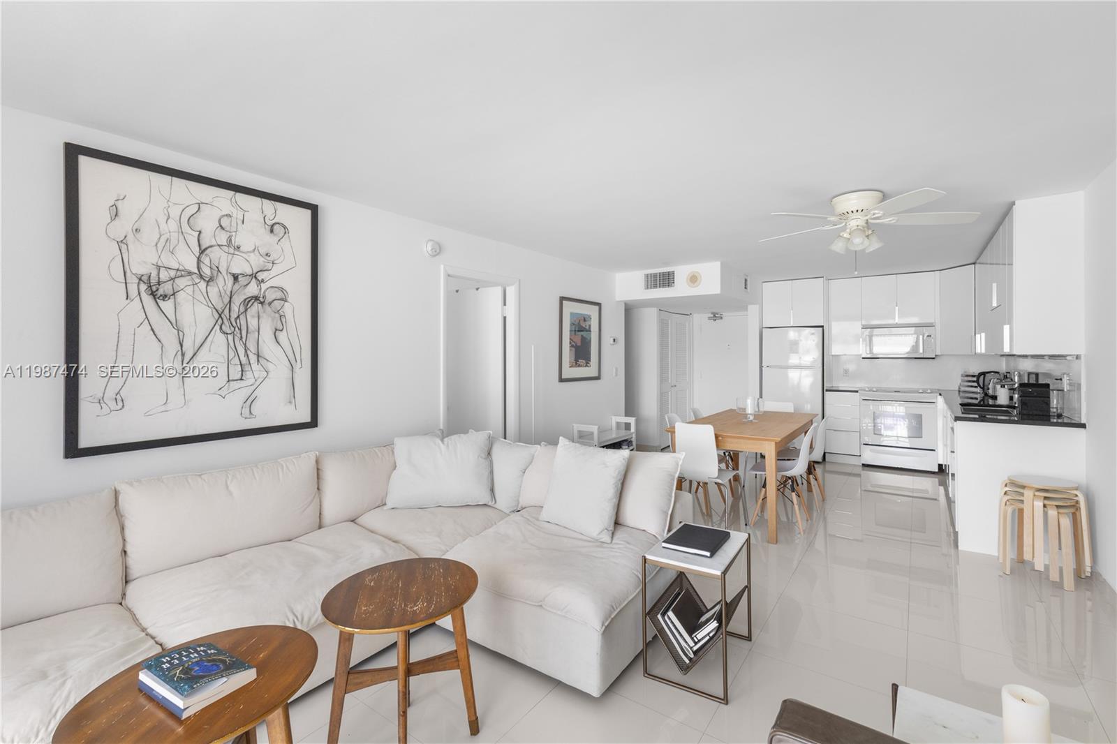 A bright, open-concept living and dining area features white furniture, tile floors, and modern cabinetry — 345 Ocean Dr # 607, Miami Beach FL 33139, MIAMI BEACH, FL