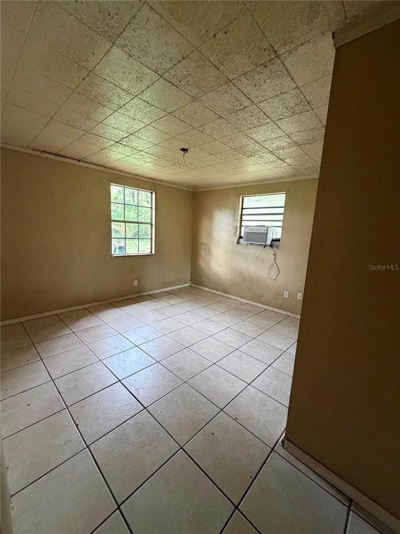 A room with beige walls, a tiled floor, and a drop ceiling with a window unit — 9314 MANGO STREET, NEW PORT RICHEY, FL