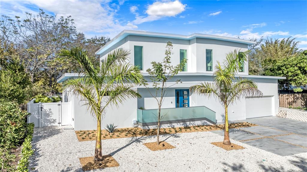 A modern two-story white house features a blue front door, glass railing, and palm trees — 2585 CLEMATIS STREET, SARASOTA, FL