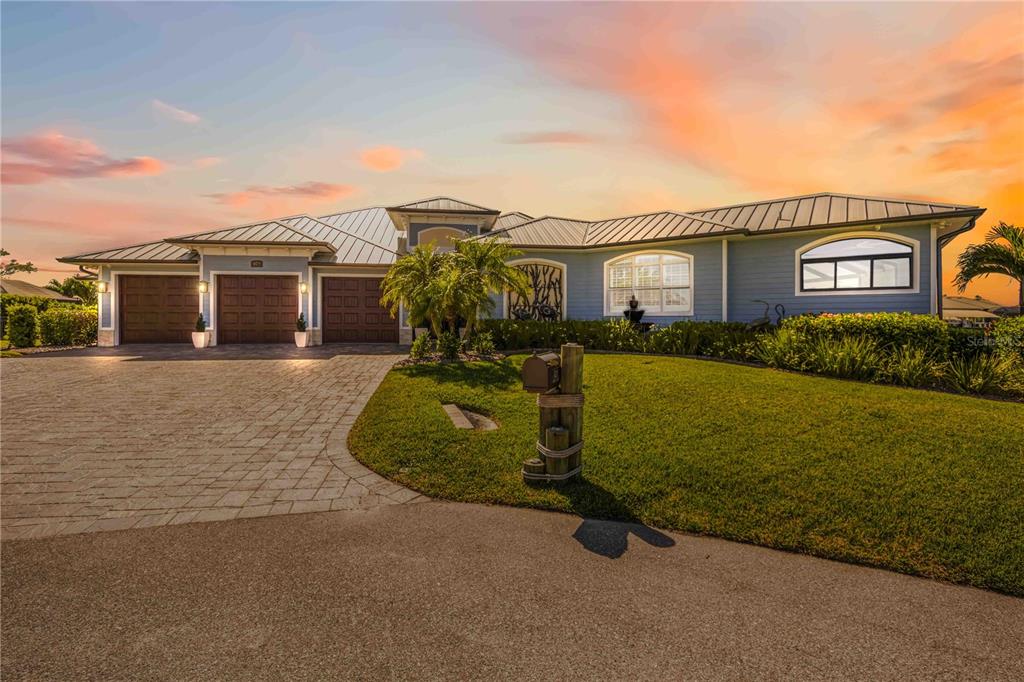 A blue single-story house with a metal roof, three garage doors, and a paved driveway — 4179 SPIRE STREET, PORT CHARLOTTE, FL