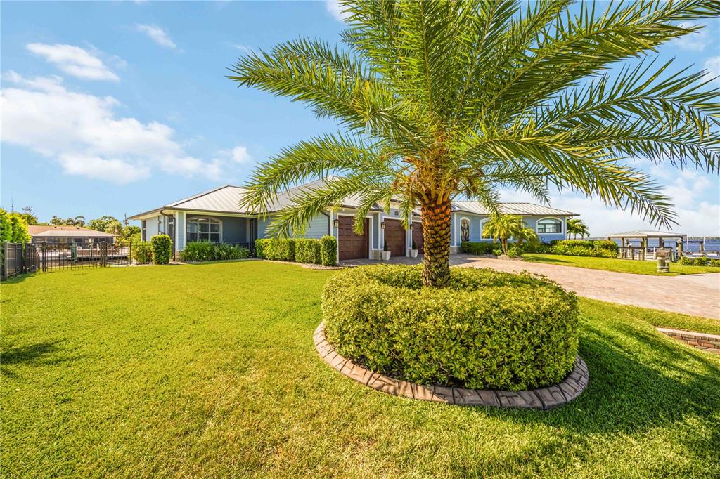 A palm tree stands in a circular garden bed in front of a waterfront house — 4179 SPIRE STREET, PORT CHARLOTTE, FL