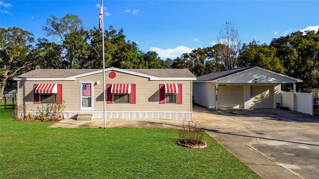 A single-story tan mobile home with red shutters and an attached two-car carport — 18845 SE 18TH PLACE, SILVER SPRINGS, FL