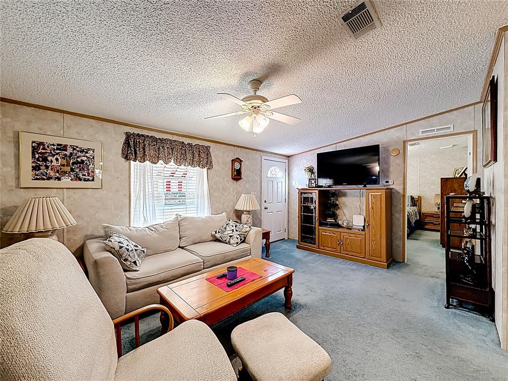 A living room features a beige sofa, a wooden coffee table, and a ceiling fan — 18845 SE 18TH PLACE, SILVER SPRINGS, FL