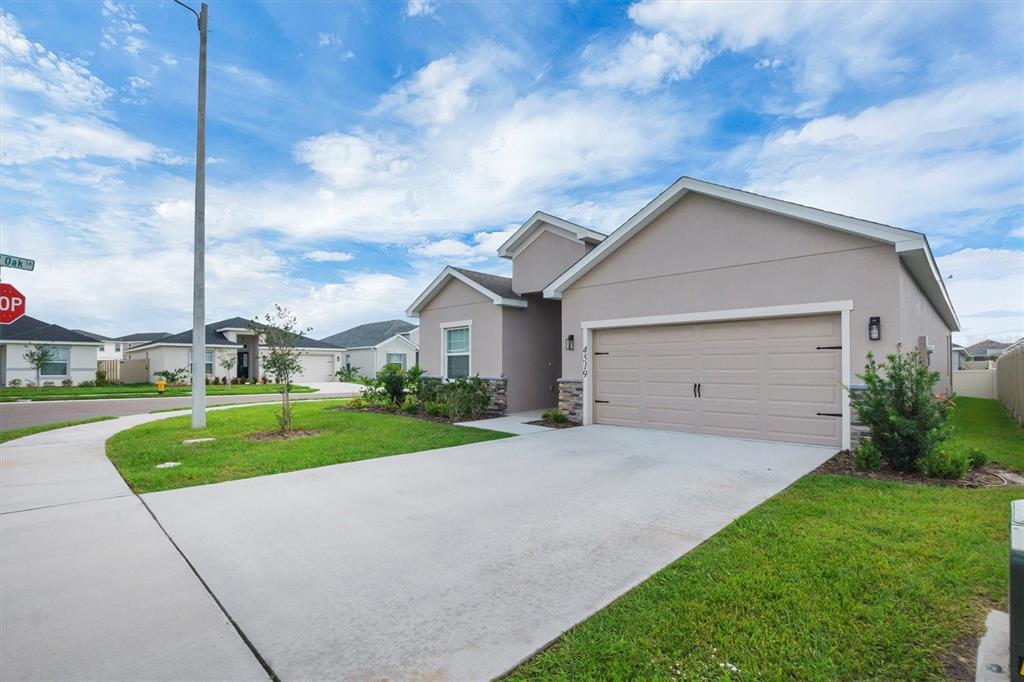 A single-story suburban house with a beige stucco exterior and a two-car garage — 4519 RAPALLO AVENUE, WINTER HAVEN, FL