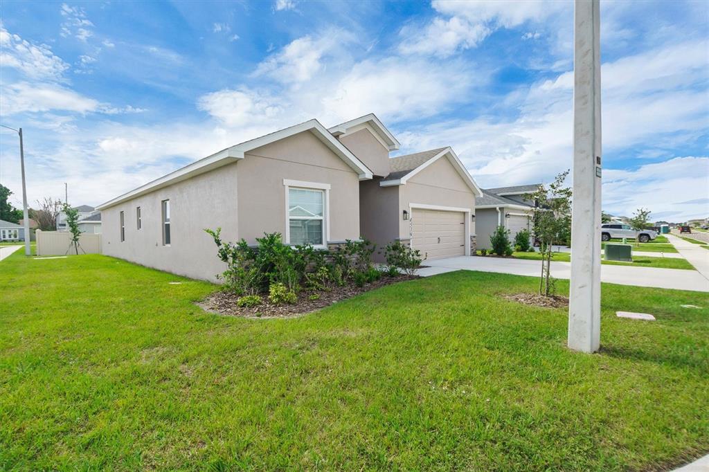 A beige single-story house with a two-car garage and a green lawn — 4519 RAPALLO AVENUE, WINTER HAVEN, FL