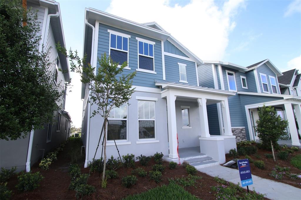A two-story house with blue siding and a covered front porch stands on a lawn — 9434 HARTLINE WAY, ORLANDO, FL