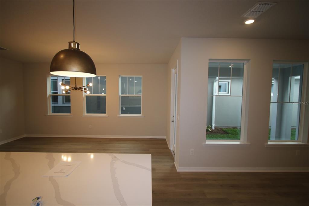 A bright room features light wood flooring, a modern pendant light, and several large windows — 9434 HARTLINE WAY, ORLANDO, FL