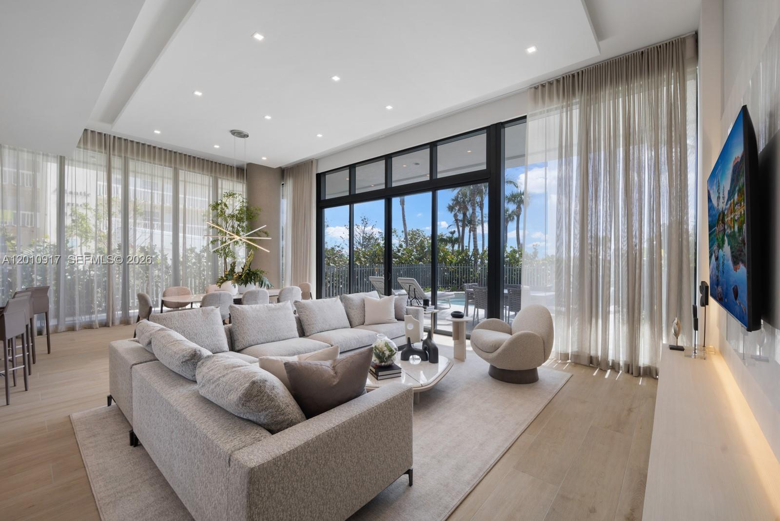 A modern living and dining area features floor-to-ceiling windows overlooking a patio and pool — 900 N Ocean Blvd # 106, Pompano Beach FL 33062, POMPANO BEACH, FL