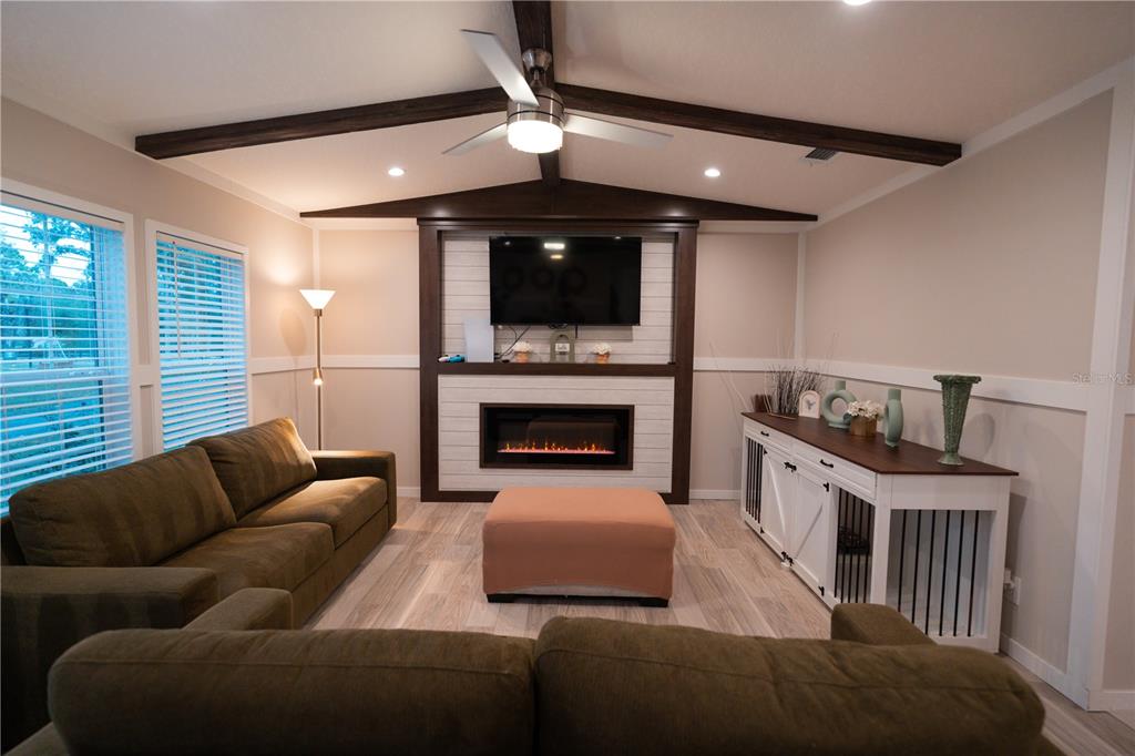 A living room features a fireplace, a mounted television, a ceiling fan, and a sofa — 7670 NE 97TH COURT, BRONSON, FL