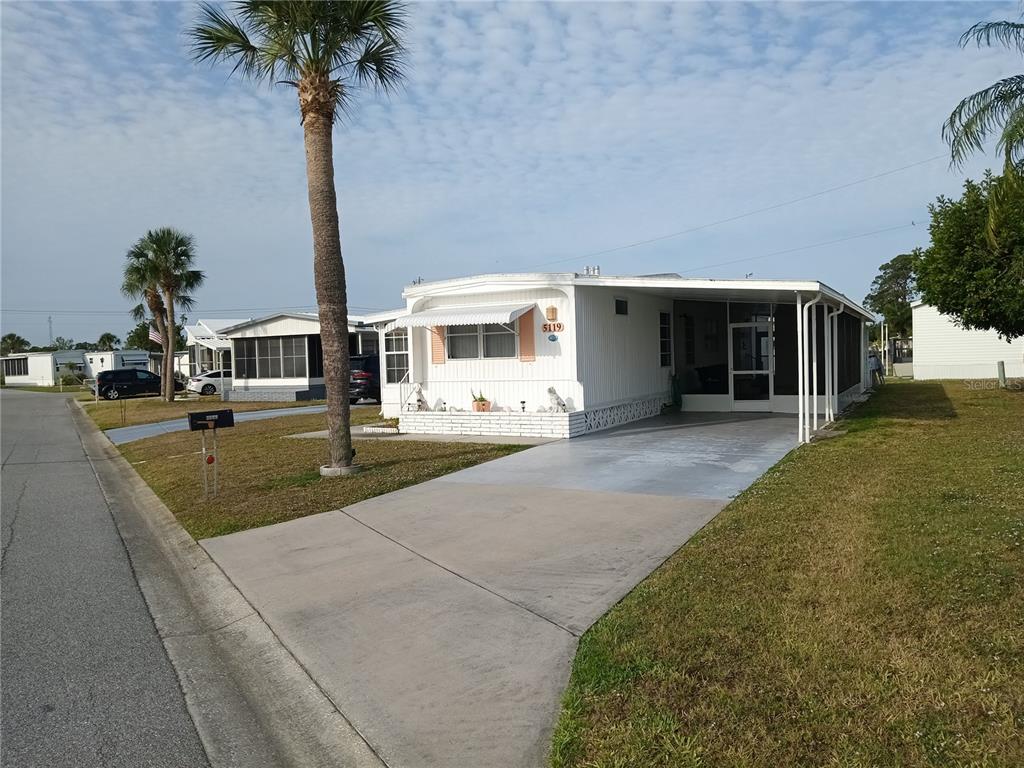A white mobile home with a concrete driveway, attached carport, and a palm tree — 5119 GLEN ECHO AVENUE, SARASOTA, FL
