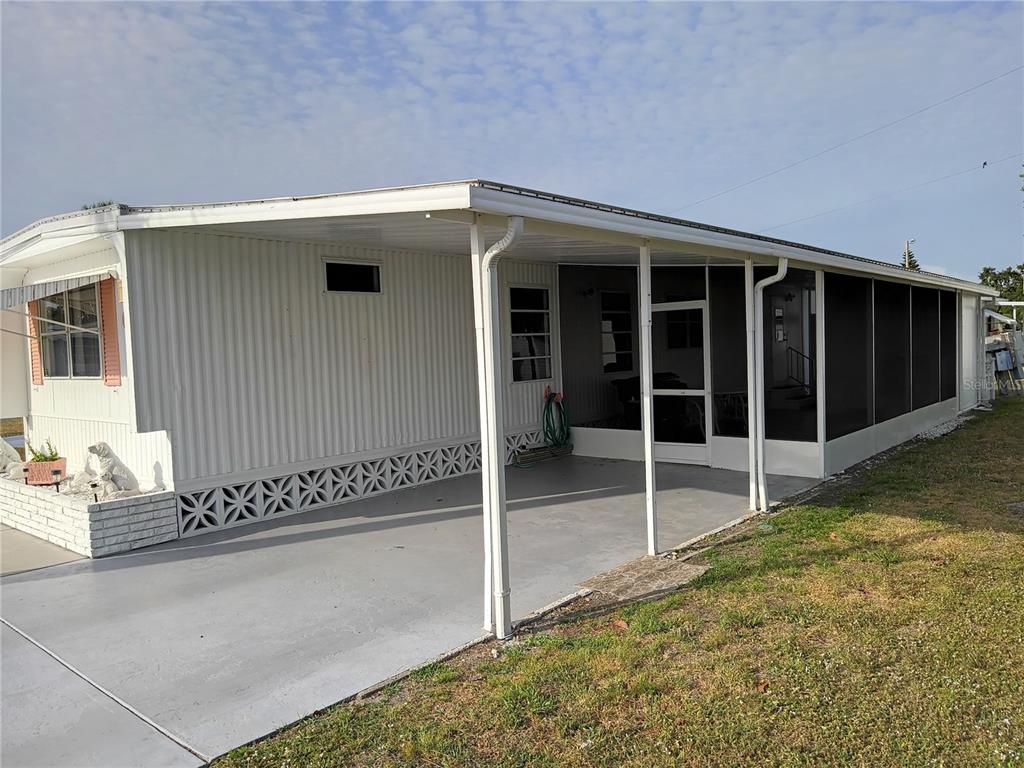 A mobile home exterior features a covered carport and an attached screened-in porch — 5119 GLEN ECHO AVENUE, SARASOTA, FL
